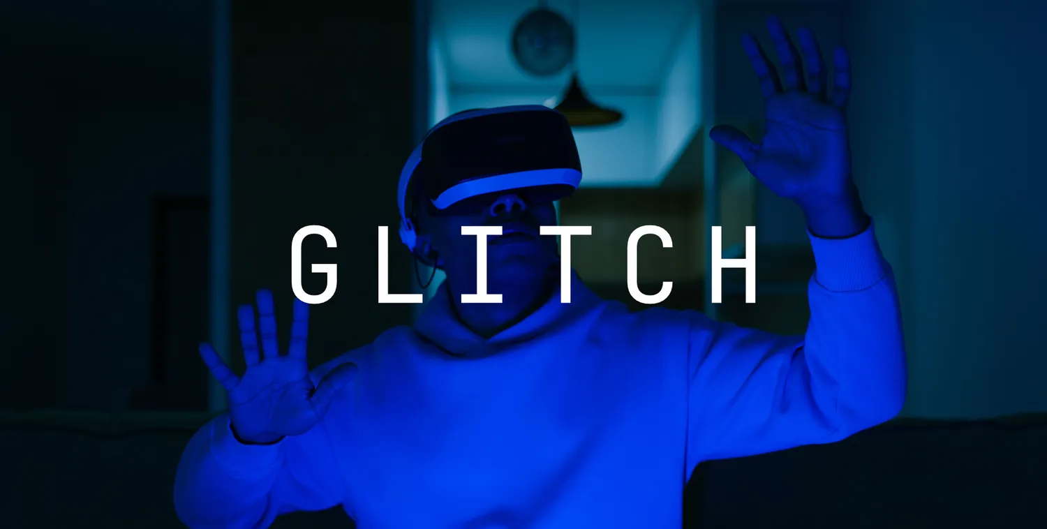 A near-clean roll: the person in the VR headset still reads, hands raised, the word GLITCH crisp across the middle